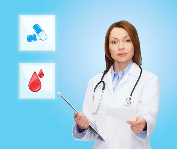 Smiling doctor or nurse pointing to pills icon — Stock Photo, Image