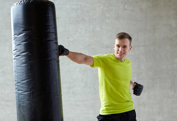 Young man in gloves boxing with punching bag — Stock Photo, Image