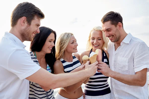 Amigos sorrindo comer sorvete na praia — Fotografia de Stock