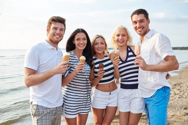 Uśmiechnięty znajomych jeść lody na plaży — Zdjęcie stockowe