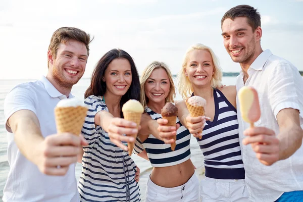 Lachende vrienden eten van ijs op strand — Stockfoto