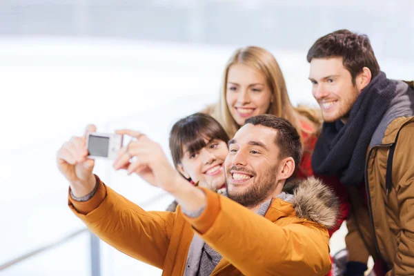 Happy friends with camera on skating rink — Stock Photo, Image