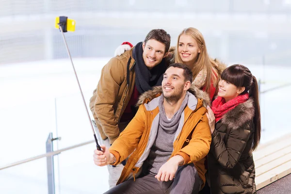 Happy friends with smartphone on skating rink — Stock Photo, Image