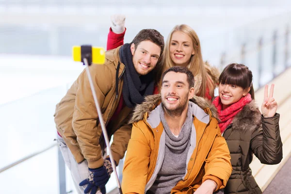 Amici felici con smartphone sulla pista di pattinaggio — Foto Stock