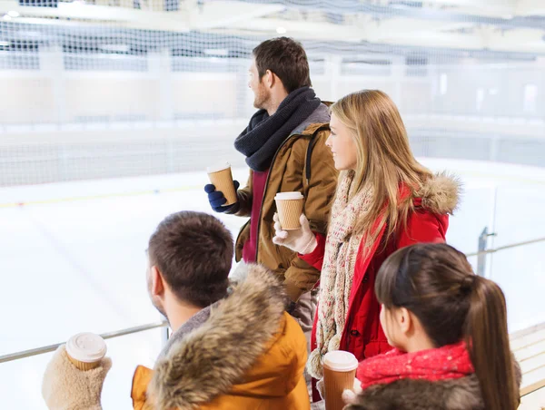 Happy friends with coffee cups on skating rink — Stock Photo, Image