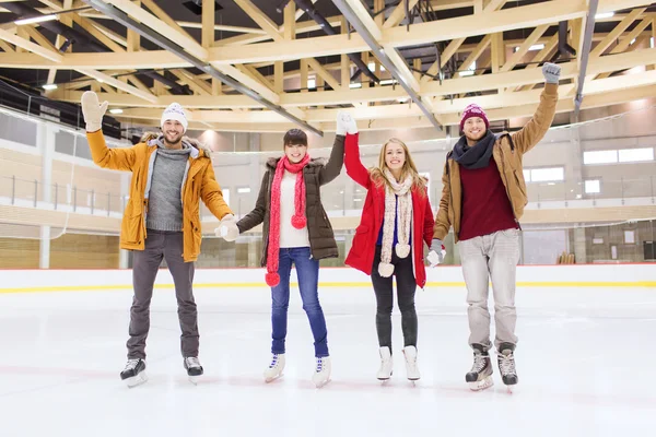 Amis heureux agitant les mains sur la patinoire — Photo