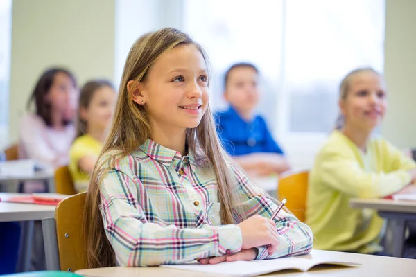 Grupo de escolares com cadernos em sala de aula — Fotografia de Stock