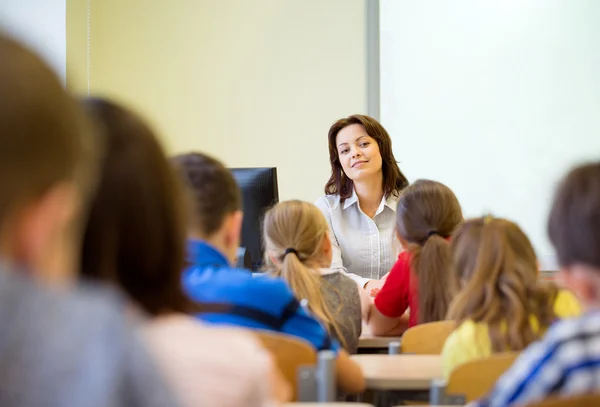 Gruppo di scolari alzare le mani in classe — Foto Stock