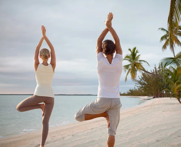 Paar maken van yoga oefeningen op strand van rug — Stockfoto