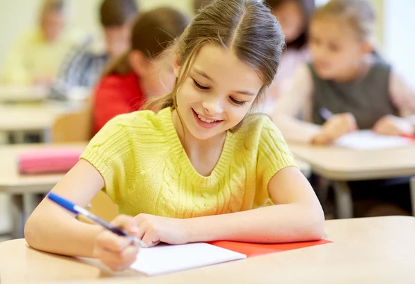 Group of school kids writing test in classroom Stock Picture