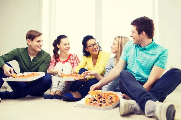 Fem leende och äta pizza hemma — Stockfoto
