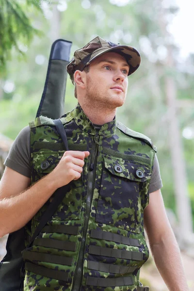 Young soldier or hunter with gun in forest — Stock Photo, Image