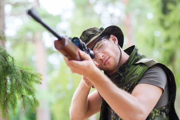 Jovem soldado ou caçador com arma na floresta — Fotografia de Stock