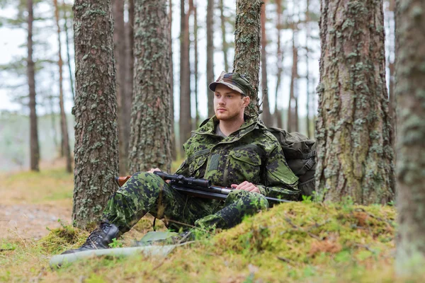 Young soldier or hunter with gun in forest — Stock Photo, Image