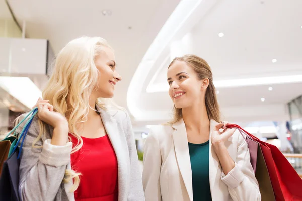 Happy young women with shopping bags in mall — Stock Photo, Image