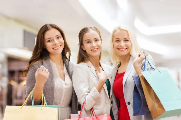 Gelukkig jonge vrouwen met boodschappentassen in winkelcentrum — Stockfoto