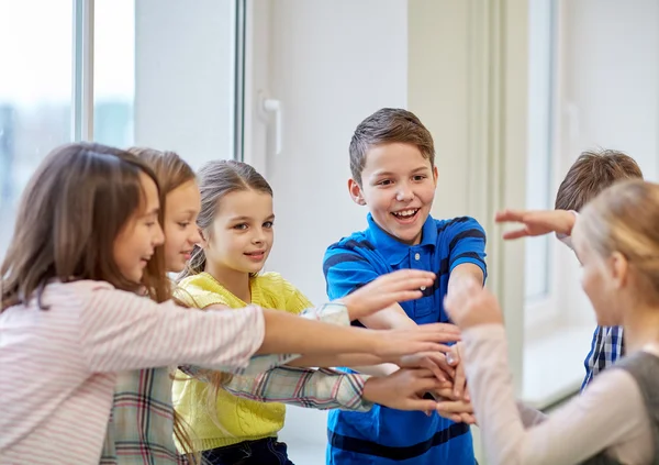 Group of smiling school kids putting hands on top Royalty Free Stock Photos