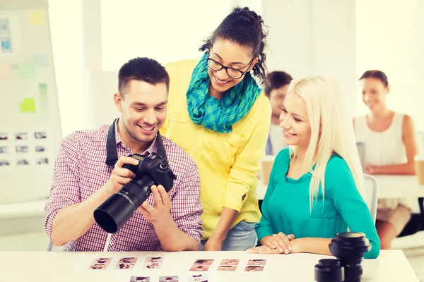 Улыбающаяся команда с фотокамерой, работающая в офисе — стоковое фото