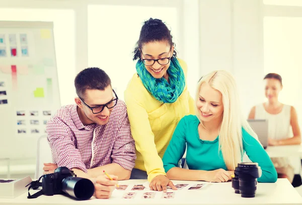 Smiling team with printed photos working in office — Stock Photo, Image