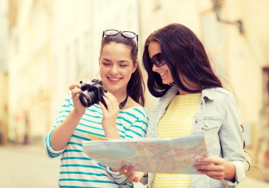 smiling teenage girls with map and camera clipart