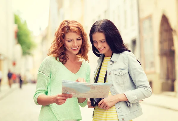 Smiling teenage girls with map and camera — Stock Photo, Image