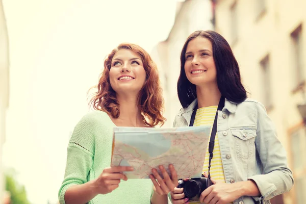 Smiling teenage girls with map and camera — Stock Photo, Image