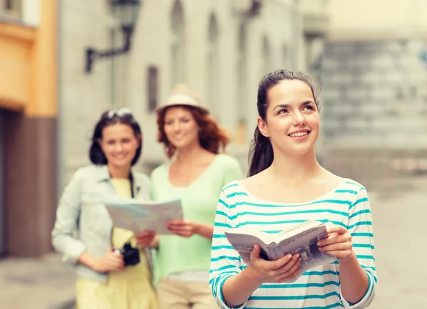 Smiling teenage girls with city guides and camera — Stock Photo, Image