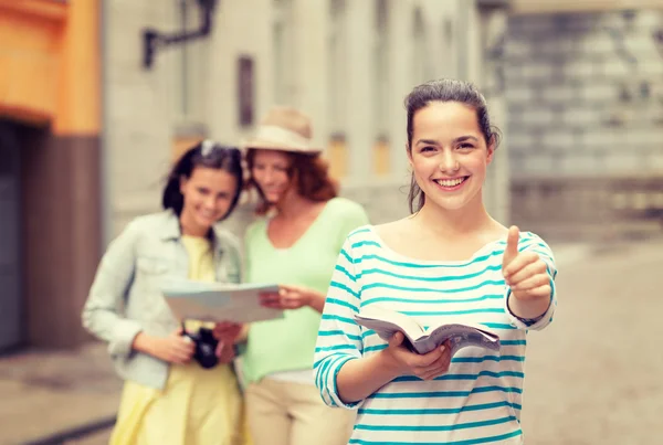 Smiling teenage girls with city guide and camera — Stock Photo, Image