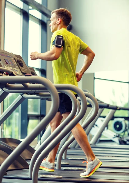 Homme avec smartphone faisant de l'exercice sur tapis roulant en salle de gym — Photo