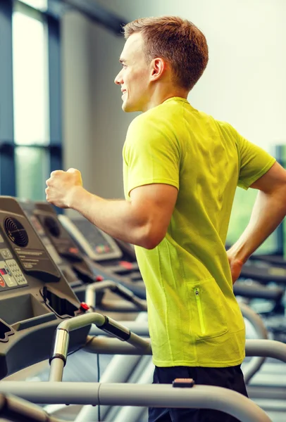 Hombre sonriente haciendo ejercicio en la cinta de correr en el gimnasio — Foto de Stock