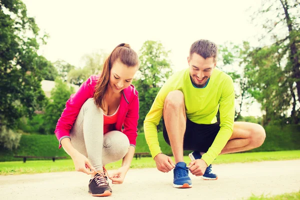 Coppia sorridente allacciatura lacci delle scarpe all'aperto — Foto Stock