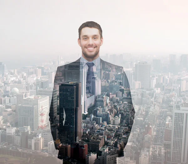 Smiling young buisnessman over city background — Stock Photo, Image