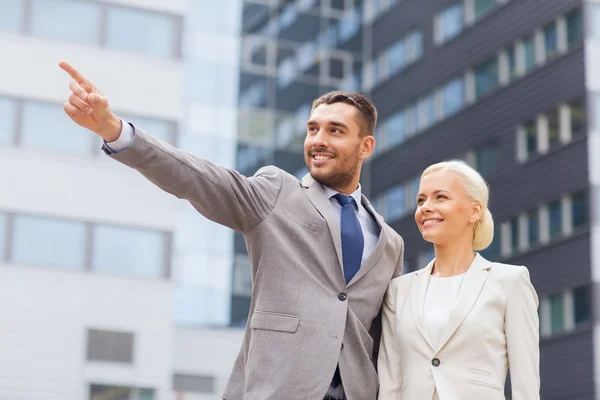 Hombres de negocios sonrientes de pie sobre el edificio de oficinas — Foto de Stock