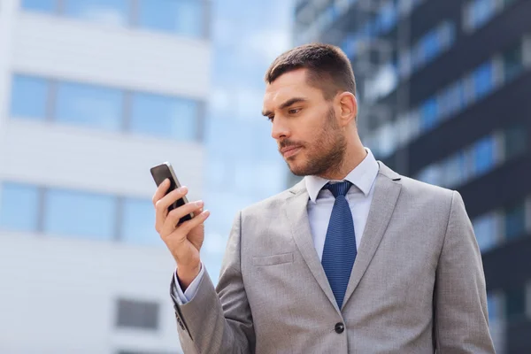 Серьезный бизнесмен со смартфоном на открытом воздухе — стоковое фото