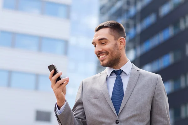 Hombre de negocios sonriente con teléfono inteligente al aire libre — Foto de Stock