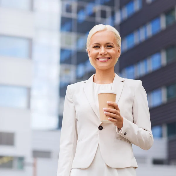 Glimlachende zakenvrouw met papier kop buitenshuis — Stockfoto