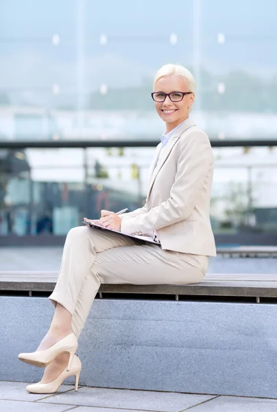 Jeune femme d'affaires souriante avec bloc-notes à l'extérieur — Photo