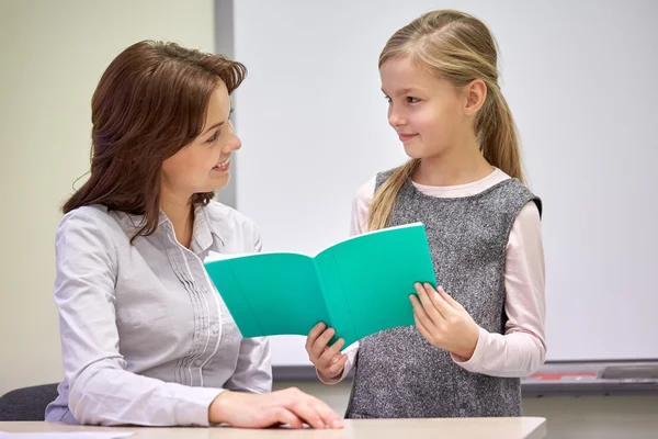 Schulmädchen mit Notizbuch und Lehrer im Klassenzimmer — Stockfoto
