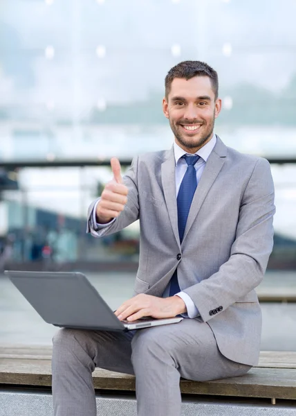 Homem de negócios sorrindo trabalhando com laptop ao ar livre — Fotografia de Stock