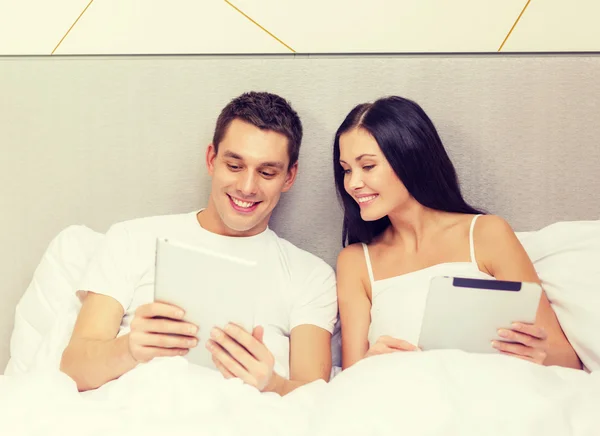Sorrindo casal na cama com computadores tablet pc — Fotografia de Stock