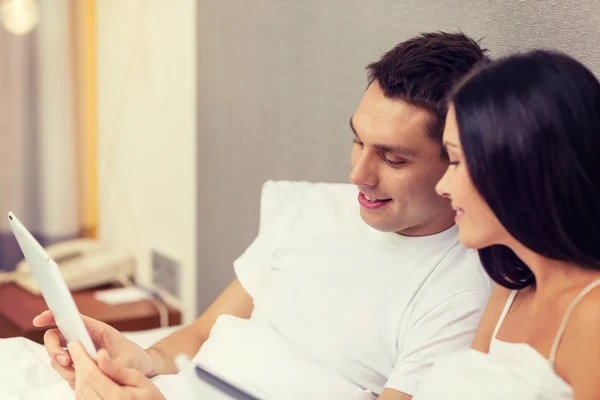 Lachende paar in bed met tablet pc-computers — Stockfoto