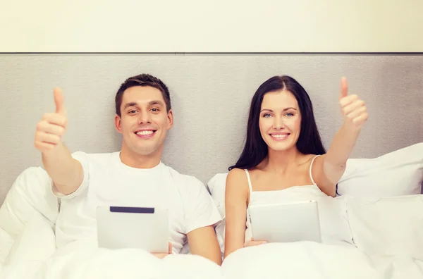 Usmívající se pár v posteli s počítači tablet pc — Stock fotografie