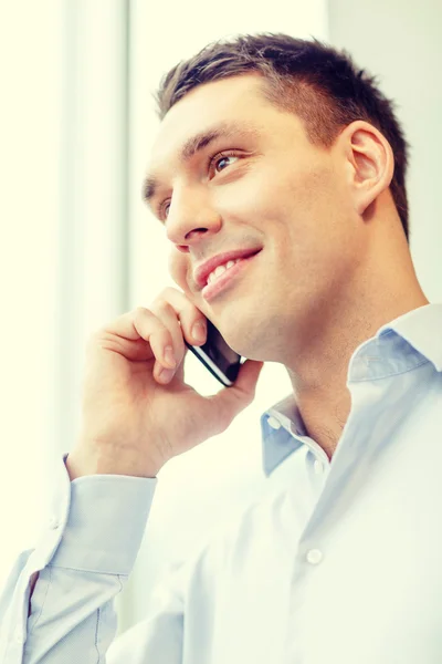 Homme d'affaires souriant avec smartphone au bureau — Photo