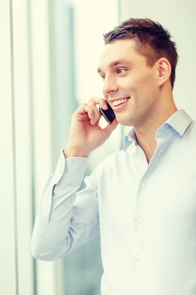 Smiling businessman with smartphone in office — Stock Photo, Image