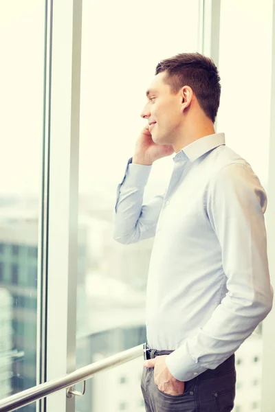 Smiling businessman with smartphone in office — Stock Photo, Image