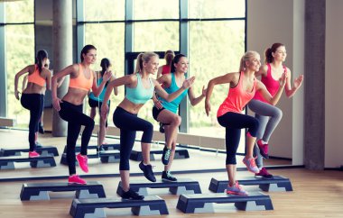 group of women working out with steppers in gym clipart