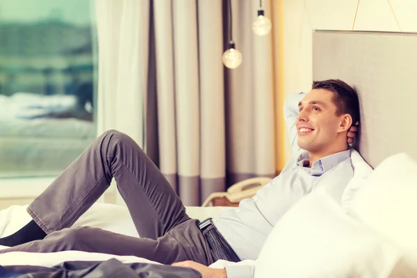 ホテルの部屋でベッドに横たわっている幸せの実業家 — ストック写真