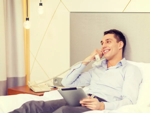 Empresário com tablet pc e telefone no quarto de hotel — Fotografia de Stock