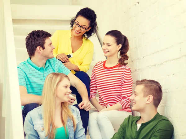 Estudantes sorridentes com smartphone tendo discussão — Fotografia de Stock