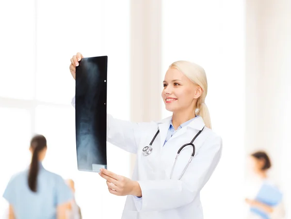 Doctora sonriente mirando la imagen de rayos X — Foto de Stock